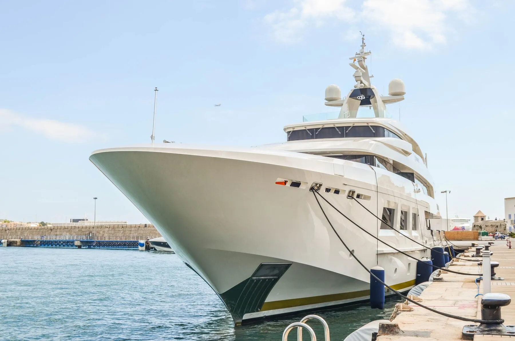Bow of a superyacht berthed in a marina at sunset